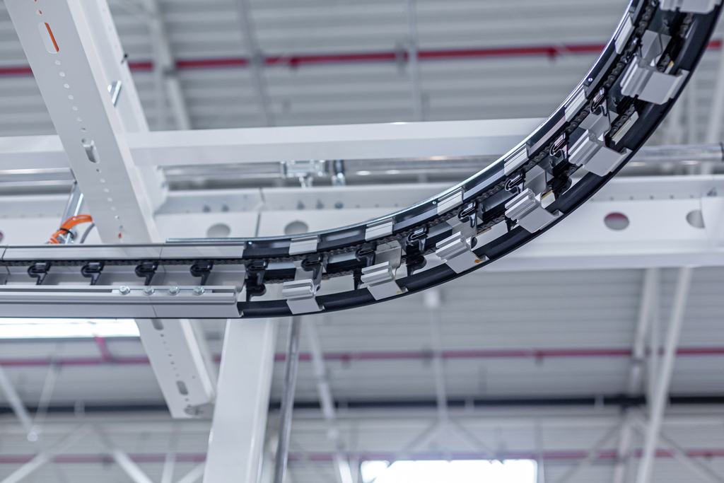 Curved section of an overhead garment conveyor system showing rail design and directional flow.